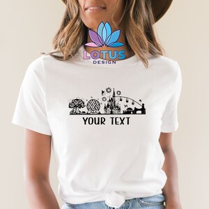 K&ouml;nnte beinhalten: Wei&szlig;es T-Shirt mit einer schwarzen Silhouette der Disney World Skyline, einschlie&szlig;lich Cinderella's Castle, Spaceship Earth und dem Tree of Life. Der Text "YOUR TEXT" ist unterhalb der Skyline gedruckt.