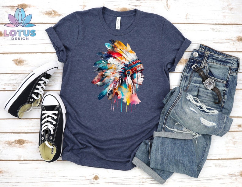 May include: A navy blue t-shirt with a watercolor illustration of a Native American headdress with colorful feathers. The headdress is dripping with paint.