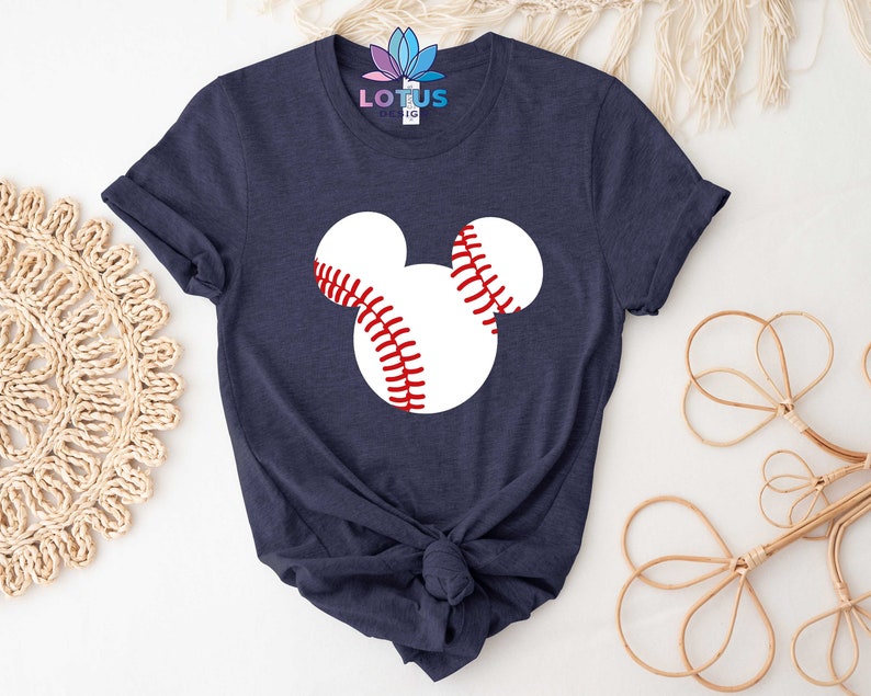 May include: A navy blue t-shirt with a white baseball-shaped Mickey Mouse design. The baseballs have red stitching.