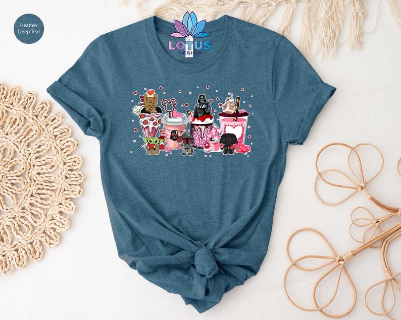 May include: A heather deep teal t-shirt with a graphic of Star Wars characters in Valentine's Day themed cups. The characters include Darth Vader, Yoda, Chewbacca, R2-D2, and a Stormtrooper.