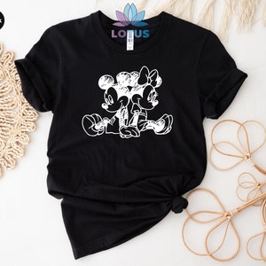 Pode incluir: Camiseta preta com um gr&aacute;fico branco do Mickey Mouse e da Minnie Mouse sentados juntos. O gr&aacute;fico &eacute; um estilo de desenho de linha simples.