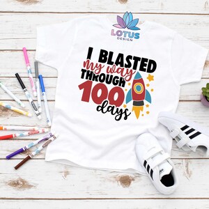 May include: White t-shirt with a rocket ship graphic and the text "I blasted my way through 100 days".
