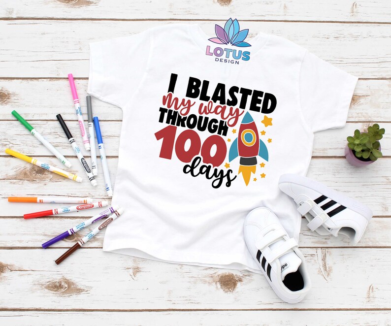 May include: White t-shirt with a rocket ship graphic and the text "I blasted my way through 100 days".