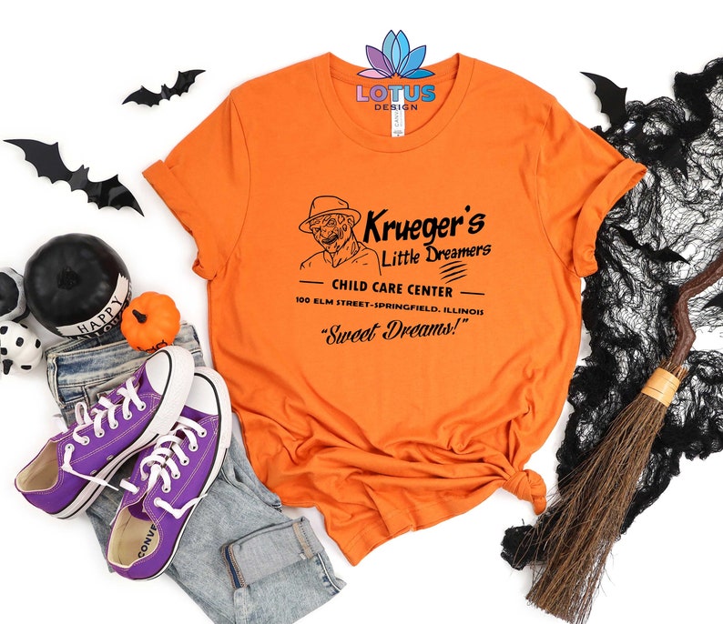 May include: Orange t-shirt with a black and white graphic of Freddy Krueger. The graphic says "Krueger's Little Dreamers Child Care Center 100 Elm Street-Springfield, Illinois "Sweet Dreams!"