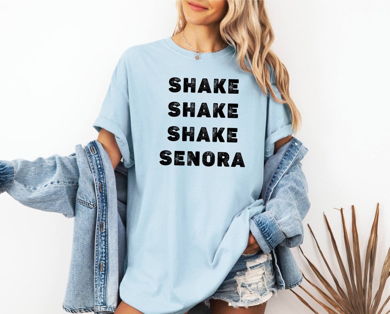 May include: A light blue t-shirt with the text "SHAKE SHAKE SHAKE SENORA" printed in black.