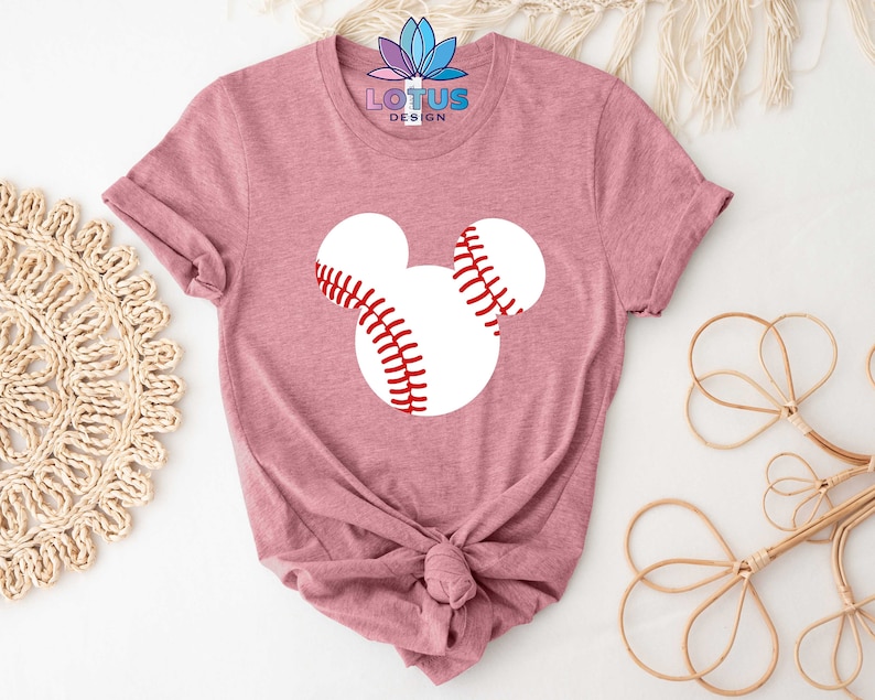 May include: A pink t-shirt with a white baseball Mickey Mouse design. The shirt is tied in a knot at the bottom.