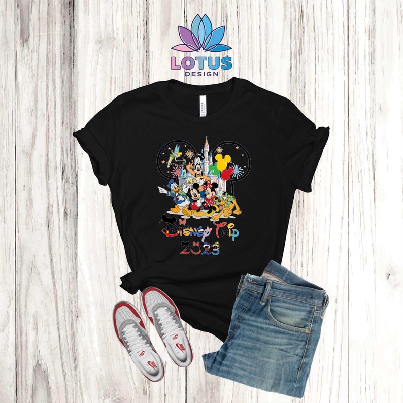 Puede incluir: Camiseta negra con un gr&aacute;fico de Mickey Mouse y otros personajes de Disney frente al Castillo de Cenicienta. El texto "My Disney Trip 2023" est&aacute; impreso debajo de los personajes.