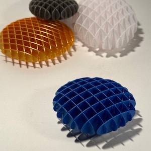 May include: Four decorative spheres, each with a different color and a grid pattern. The spheres are made of a hard plastic material and are arranged in a row on a white surface. The colors are orange, white, gray, and blue.