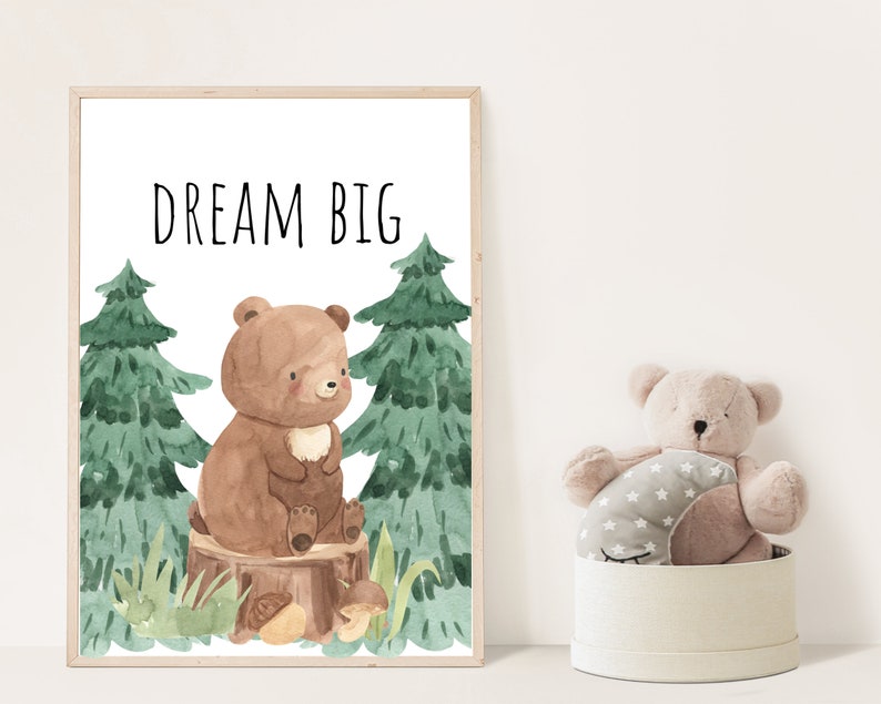 May include: A watercolor illustration of a brown bear sitting on a tree stump in a forest. The bear is surrounded by green trees and mushrooms. The text "DREAM BIG" is written in black at the top of the image.