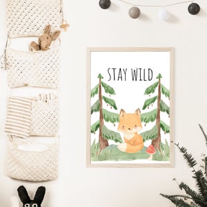 May include: A watercolor print featuring a cute fox sitting in a forest with the text "STAY WILD" above it. The print is framed in a light wood frame.