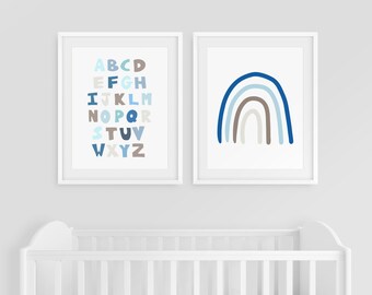 May include: Two framed prints, one with a blue and gray alphabet and the other with a blue and gray rainbow, hanging above a white crib.