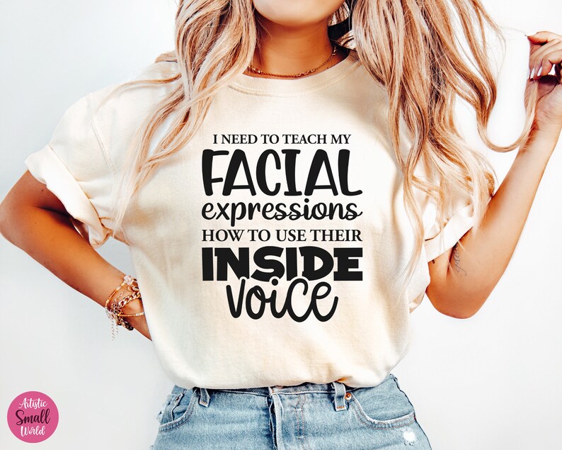May include: A white t-shirt with black text that reads "I need to teach my facial expressions how to use their inside voice."