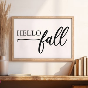Puede incluir: Una impresi&oacute;n enmarcada con el texto "HELLO fall" en una fuente cursiva negra sobre un fondo blanco. El marco es de madera marr&oacute;n claro.