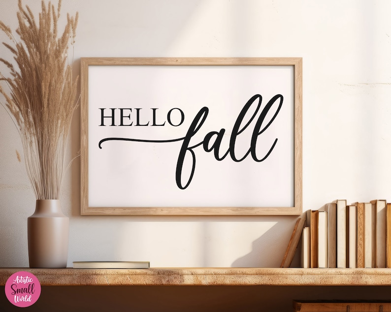 Puede incluir: Una impresi&oacute;n enmarcada con el texto "HELLO fall" en una fuente cursiva negra sobre un fondo blanco. El marco es de madera marr&oacute;n claro.