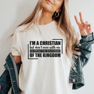 May include: White t-shirt with black text that reads "I'm a Christian but don't mess with me I'm from the Southside of the Kingdom."