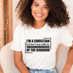 May include: White t-shirt with a black graphic that reads "I'M A CHRISTIAN but don't mess with me I'M FROM THE SOUTHSIDE OF THE KINGDOM"
