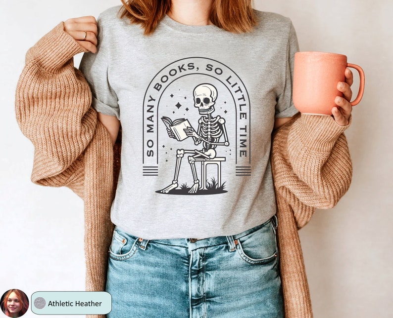 May include: A gray t-shirt with a skeleton reading a book. The text on the shirt reads "So many books, so little time".
