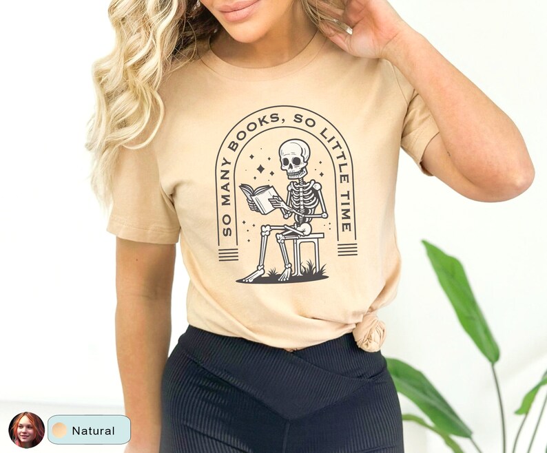 May include: A tan t-shirt with a black and white graphic of a skeleton reading a book. The graphic says "So many books, so little time".