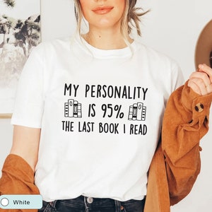 May include: White t-shirt with the text "My personality is 95% the last book I read" and a graphic of a stack of books.