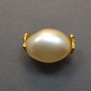 May include: A gold-tone brooch with a large, white faux pearl in the center.