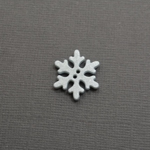 May include: A silver glitter snowflake button with a raised center.