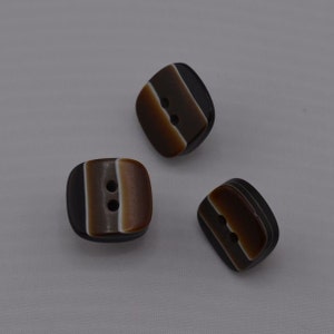 May include: Three brown and white striped square buttons with two holes each.