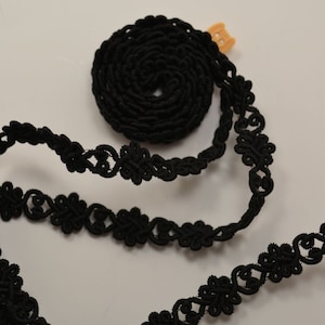 May include: Black elastic trim with a delicate floral design. The trim is coiled and ready to be used for sewing or crafting projects.