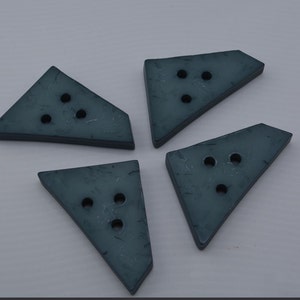 May include: Four dark blue triangle-shaped buttons with three holes each.