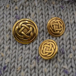 May include: Three gold-colored buttons with a Celtic knot design. The buttons are round and have a raised design.