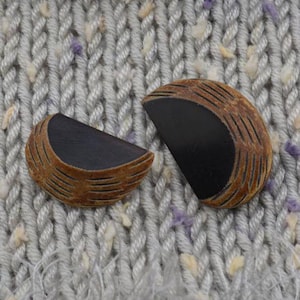 May include: Two brown and black half-circle buttons with a wood grain texture.