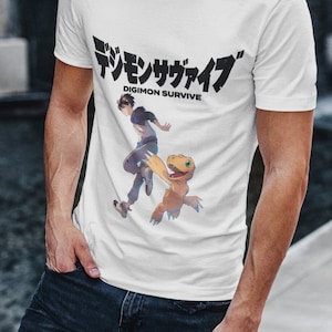 May include: White t-shirt with a black graphic print of a character from the anime Digimon Survive. The text "Digimon Survive" is printed in black below the graphic. The Japanese text "デジモンサヴァイブ" is printed above the graphic.