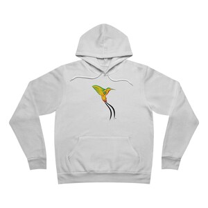 Puede incluir: Una sudadera blanca con capucha y mangas largas que presenta un gráfico de un colibrí con plumaje amarillo, verde y rojo y largas plumas negras en la cola centrado en el pecho. La sudadera incluye un bolsillo canguro y cordones a juego.
