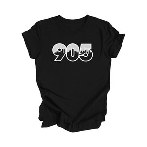 Könnte beinhalten: Schwarzes T-Shirt mit einer weißen Grafik der Nummer 905 mit einer Skyline innerhalb der Zahlen.