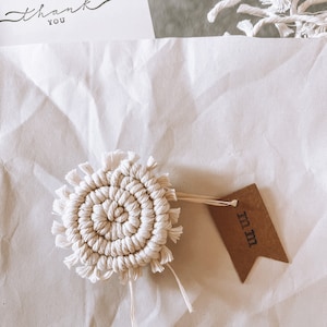 May include: A white macrame coaster with a brown tag that says "Im In".