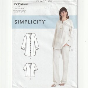 May include: A Simplicity sewing pattern envelope S9113.wmt featuring a white long-sleeve tunic and matching trousers. The package displays technical line drawings of a button-down tunic and a short-sleeve top, with sizing information for U.S. sizes 6-14.