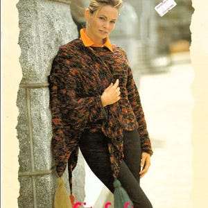 May include: A multi-colored knit poncho featuring a textured pattern in shades of black, orange, and purple, accented with long tassels at the corners. The garment is worn over an orange collared shirt and black pants, with the text Berroco Brochure #169.