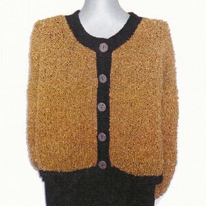 May include: A long-sleeve cardigan featuring a textured, golden-brown knit body with a solid black trim along the round neckline, cuffs, and hem. The front closure consists of five round, dark-colored buttons aligned vertically on a black placket.