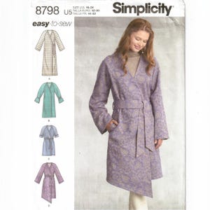 May include: A Simplicity sewing pattern envelope 8798 for an easy-to-sew wrap robe in sizes U.S. 16-24. The cover features a model wearing a long-sleeved, knee-length purple robe with a paisley pattern, a V-neckline, and a matching tie belt.