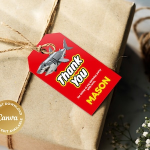 Puede incluir: Etiqueta de regalo roja de agradecimiento con una ilustraci&oacute;n de tibur&oacute;n blanco y el texto "Gracias" en letras amarillas. La etiqueta tambi&eacute;n incluye el texto "por estar en mi fiesta de cumplea&ntilde;os con amor, MASON".