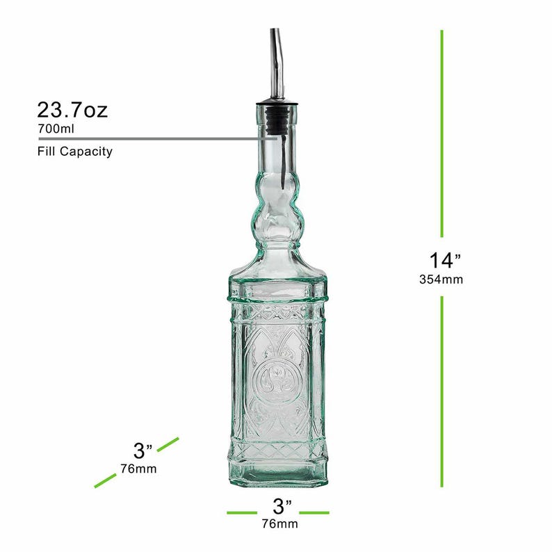 Op de afbeelding: Een heldere glazen fles met een roestvrijstalen tuit, ontworpen voor het doseren van vloeistoffen. De fles is 354 mm hoog, 76 mm breed en heeft een vulcapaciteit van 700 ml. Het heeft een reli&euml;f ontwerp en een zwarte stopper.