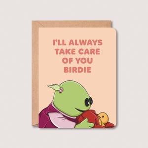 May include: A greeting card with a light pink background featuring a green alien-like character with a pink shirt holding a small yellow bird. The text on the card reads "I'll always take care of you birdie."