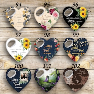 May include: Set of ten heart-shaped bottle openers with various designs. The designs include floral patterns, sunflowers, a couple in a forest, a couple in a wedding dress, and a couple's initials. The bottle openers are all white with a silver bottle opener.