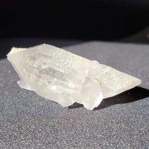 May include: A clear quartz crystal cluster with multiple points, showing a natural, raw, and unpolished finish.