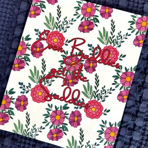 May include: A white canvas print featuring a floral design with pink and purple flowers and green leaves. The text "Even Baddies get the Baddies" is written in a cursive red font.