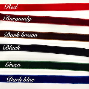 May include: Six horizontal strips of velvet ribbon in red, burgundy, dark brown, black, green, and dark blue. Each ribbon is labelled with its corresponding colour name in white script text, providing a clear visual guide for these fabric options.