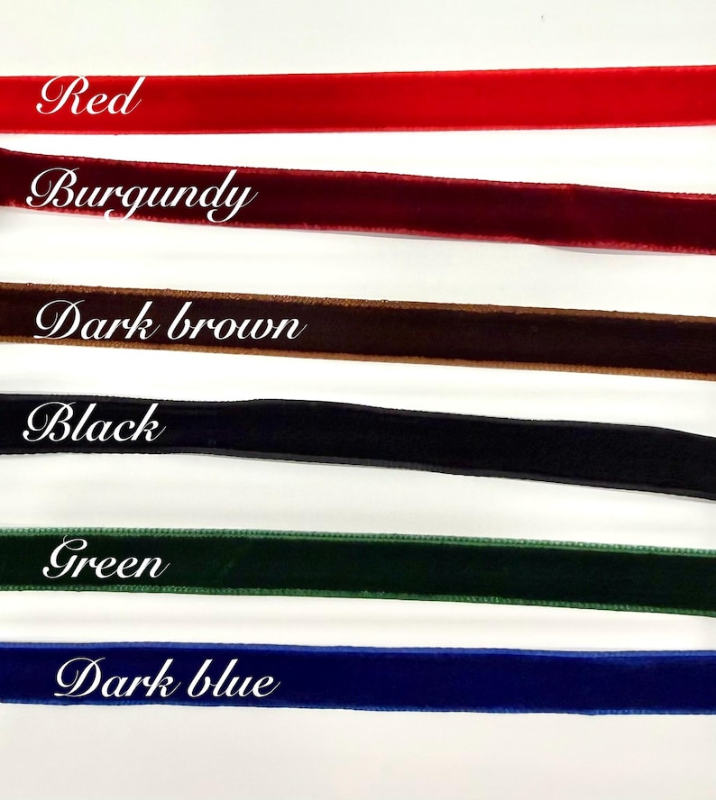 May include: Six horizontal strips of velvet ribbon in red, burgundy, dark brown, black, green, and dark blue. Each ribbon is labelled with its corresponding colour name in white script text, providing a clear visual guide for these fabric options.