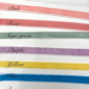 May include: A collection of eight velvet ribbons arranged horizontally in rows, each labelled with its colour: White, Pink, Rose, Sage green, Purple, Yellow, Blue, and Brown. The ribbons feature a soft, textured surface and finished edges.