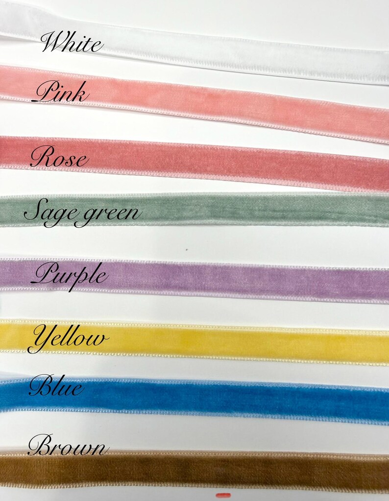 May include: A collection of eight velvet ribbons arranged horizontally in rows, each labelled with its colour: White, Pink, Rose, Sage green, Purple, Yellow, Blue, and Brown. The ribbons feature a soft, textured surface and finished edges.