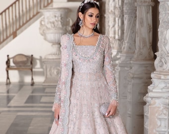 May include: A pink and silver embroidered gown with a long train and a matching dupatta. The gown features intricate floral designs and sequins.