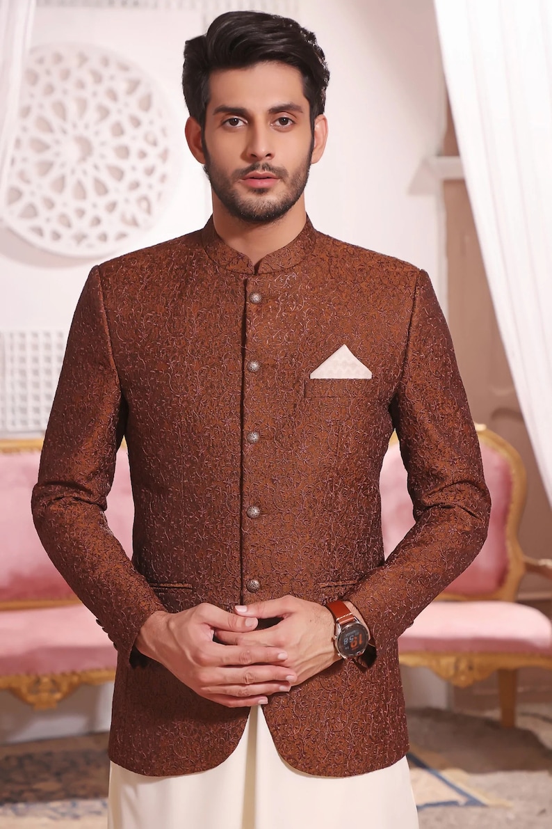 May include: A brown patterned blazer with a mandarin collar and a white pocket square. The blazer has a button closure and a single button on each cuff.